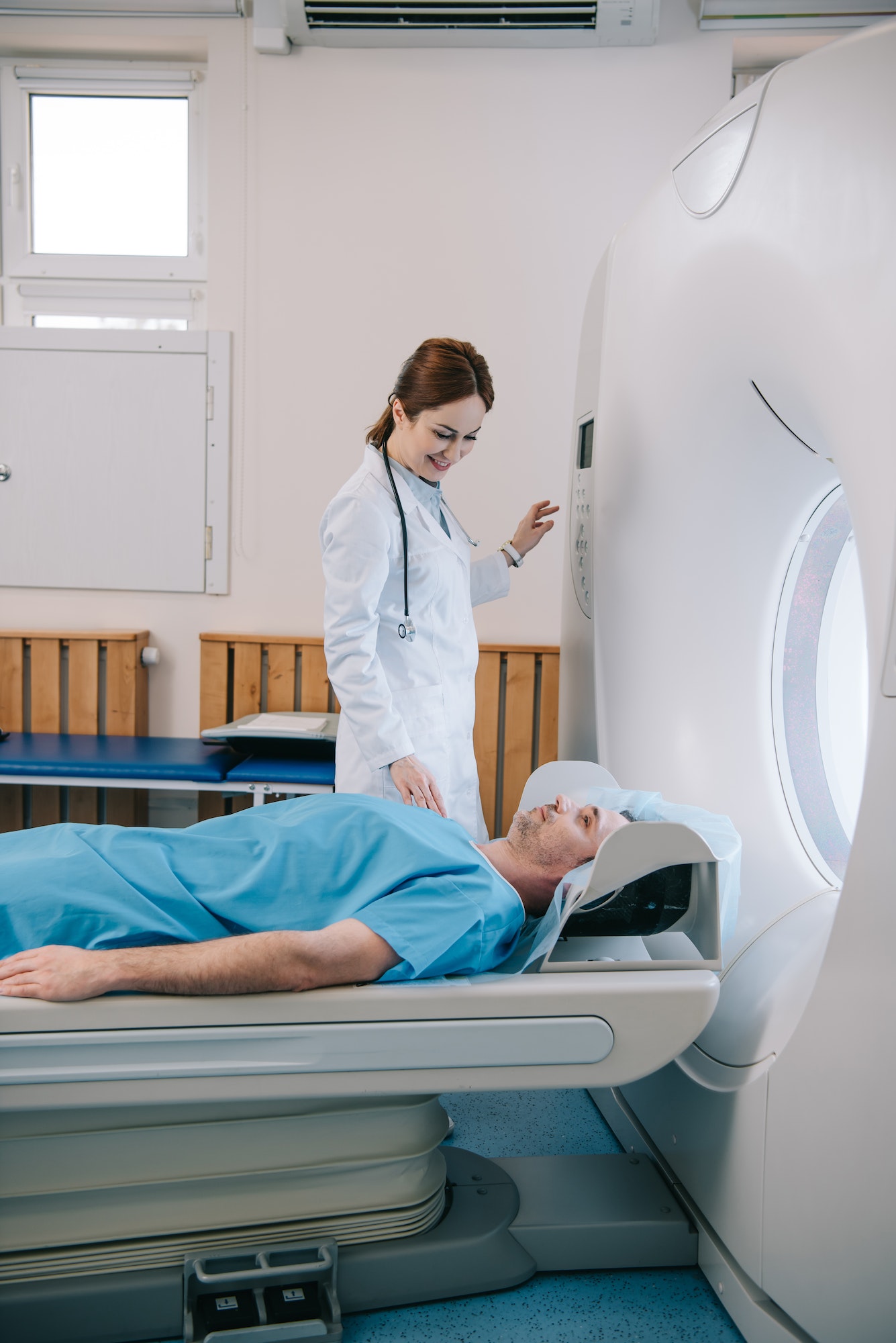 attractive smiling doctor preparing man for scanning in mri machine