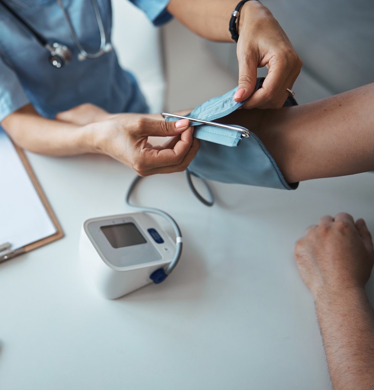 female doctor checking patient blood pressure in clinic e1682348846289